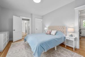 a white bedroom with a blue bed with two pillows at 232 Wood Road South Yarmouth - Cape State of Mind in South Yarmouth