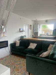 a living room with a green couch and a kitchen at Ty Cariad in Saundersfoot +15 photos