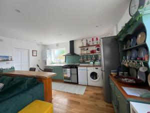 a kitchen with green cabinets and a green couch at Ty Cariad in Saundersfoot