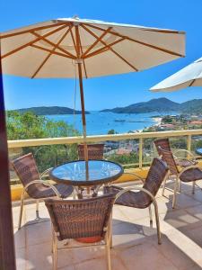 einen Tisch und Stühle mit Sonnenschirm auf dem Balkon in der Unterkunft Morro do Sol Hotel & Eventos in Porto Belo