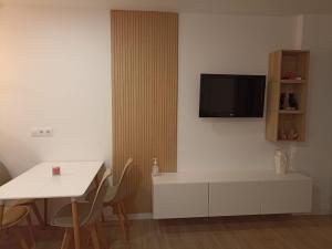 Una sala de estar con una mesa y un televisor en la pared. en Apartamento Júpiter - Minerva, en Benalmádena