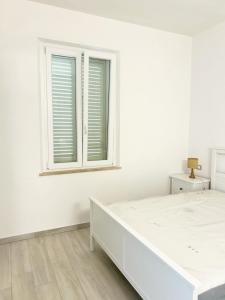 Casa Giannina a Marina di Cecina by Zoom In Earth في مارينا دي سيسينا: غرفة نوم بيضاء مع سرير ونافذة +12 صورة