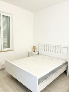 Casa Giannina a Marina di Cecina by Zoom In Earth في مارينا دي سيسينا: سرير أبيض في غرفة بيضاء مع نافذة