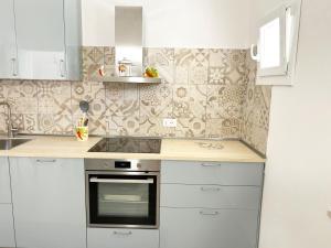 Casa Giannina a Marina di Cecina by Zoom In Earth في مارينا دي سيسينا: مطبخ بخزائن بيضاء وفرن موقد