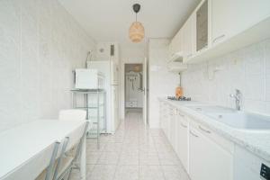 Una cocina blanca con gabinetes blancos y un fregadero. en Doorman - Spacious 2BR Paris, en Saint-Ouen