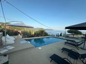 a swimming pool with chairs and an umbrella at Christie's Luxury Suites by Dandy Hospitality in Syvota