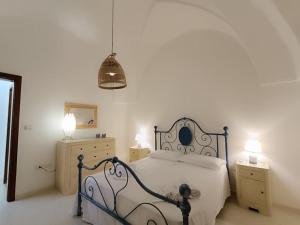 Un dormitorio blanco con una cama y dos mesitas de noche. en Adelè posto tranquillo al centro del paese, en Santa Cesarea Terme