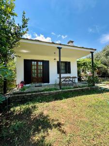 a small white house with a cat on the roof at Elgi Cottage in Chrysi Ammoudia