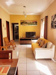 uma sala de estar com um sofá branco e uma televisão em Casa em Cabo Frio próximo à praia - Mar e Sol em Cabo Frio