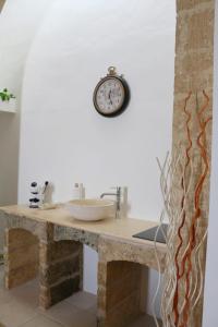 a clock on a wall above a counter with a sink at Suite Le Marie Room & Relax in Barbarano +45 photos
