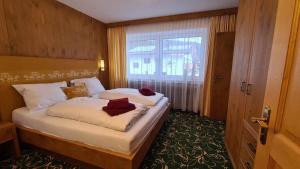 a bedroom with a bed with white sheets and a window at Gästehaus Huber in Holzgau