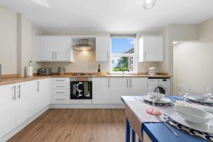 a kitchen with white cabinets and a table with wine glasses at 3BR Warwick Uni-Free Parking, Fast WiFi in Canley +19 photos