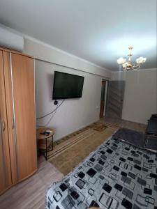 a bedroom with a bed and a flat screen tv at Уютная 1 комн квартира посуточно в Балхаше Жидебай Батыра, 11 in Balqash