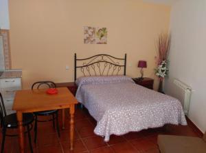 a bedroom with a bed and a wooden table at Hostal Restaurante "El Cercao" in Saúca