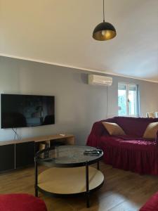 a living room with a red couch and a glass table at Apartment Šušanj in Bar