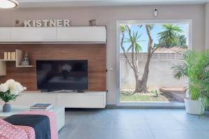 a living room with a television and a palm tree at Villa Helios Aguadulce Almeria in Roquetas de Mar