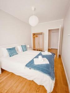 a bedroom with a large white bed with blue pillows at Alameda Apartments - Apartamento Moderno a 20 min do Porto in Trofa