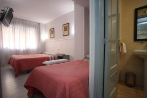 a hotel room with two beds and a window at Hostal Santa Barbara in Soria