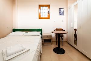 a small bedroom with a bed and a table at Στούντιο Στη Στοά Βαρβουτσή #3 in Kalamata