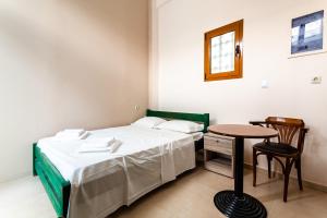 a small bedroom with a bed and a table at Στούντιο Στη Στοά Βαρβουτσή #3 in Kalamata +4 photos