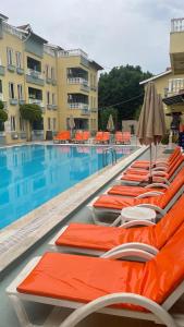 a row of orange lounge chairs next to a swimming pool at Club Sunset Apartments in Marmaris