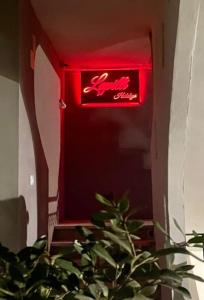 a red neon sign in a room with a plant at LAPILLI Holidays in San Giovanni la Punta