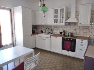a kitchen with white cabinets and a table and a sink at Villa Nonna Elisa in Pieve +3 photos