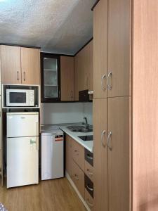 een keuken met houten kasten en witte apparatuur bij El estudio de Alejandro in Torre del Mar