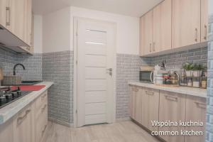 a kitchen with white cabinets and a brick wall at Remus House Apartments spokojny wypoczynek dla par, tylko pokoje 2-osobowe in Jastrzębia Góra