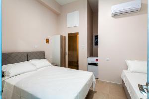 a white bedroom with two beds and a refrigerator at Στούντιο Στη Στοά Βαρβουτσή#9 in Kalamata