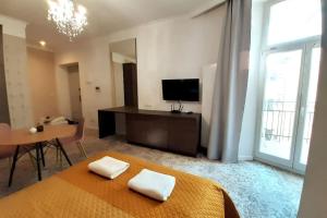 a bedroom with a bed and a table and a television at Luxury Apartment - Rakowicka R15 in Krakow