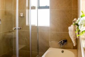 a bathroom with a shower with a toilet and a sink at Little Oasis Self Catering Cottage in Harare