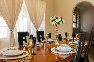 a dining room table with chairs and a vase with flowers at Little Oasis Self Catering Cottage in Harare +14 photos