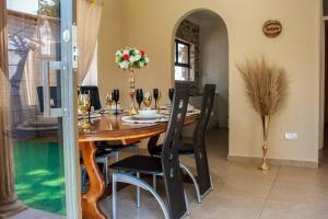 a dining room with a wooden table and chairs at Little Oasis Self Catering Cottage in Harare