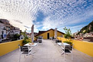a patio with tables and chairs on a balcony at Amalfi Luxury House in Amalfi