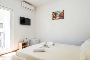 a white bedroom with a bed and a window at Sumice Inn in Petrovac na Moru