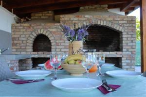 a table with plates and wine glasses and a stone oven at Crystal pool in Bihać