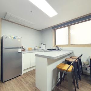 a kitchen with a refrigerator and a counter with stools at Roi Guesthouse in Seoul