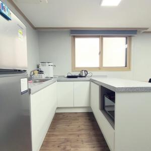 a small kitchen with white cabinets and a refrigerator at Roi Guesthouse in Seoul +60 photos