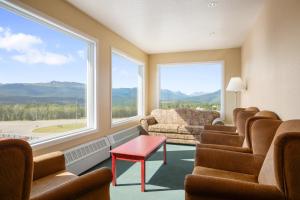 uma sala de espera com cadeiras, uma mesa e janelas grandes em Grande Cache Inn & Suites em Grande Cache