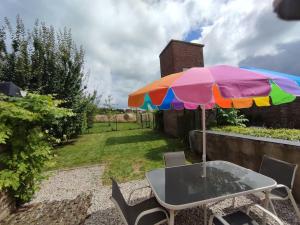 a table with a colorful umbrella in a garden at Appartement Rubrouck 1 chambre in Rubrouck