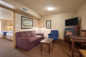 uma sala de estar com um sofá e uma televisão em Grande Cache Inn & Suites em Grande Cache