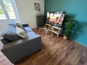 a living room with a couch and a flat screen tv at Le petit jardin de Bellune in Niort