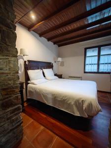 a bedroom with a bed and a stone wall at Hotel Restaurante Cabo Vidío in Oviñana