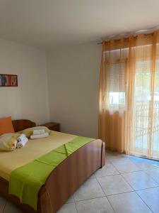 ein Schlafzimmer mit einem Bett mit einer grünen Decke und einem Fenster in der Unterkunft Apartmani Aleks in Budva