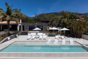 basen z białymi leżakami i parasolami w obiekcie Exceptional luxury villa in Madeira Bellissima w mieście Estreito da Calheta
