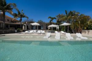 basen z białymi leżakami i parasolami w obiekcie Exceptional luxury villa in Madeira Bellissima w mieście Estreito da Calheta