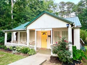 a small white house with a yellow door at Quaint City Cottage Bremen, Ga in Bremen