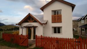 a small white house with a red fence at Kaiken - Hostel & Departamentos in El Chalten