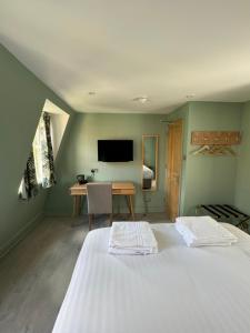 two beds in a room with a desk and a tv at Marldon Olympia Hotel in London